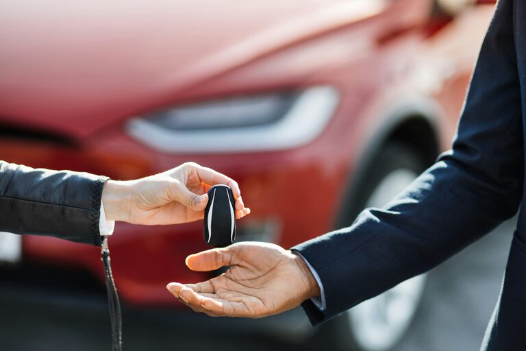 Autoschlüssel wird vor einem Fahrzeug an den Käufer übergeben