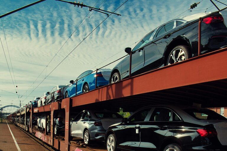 Autotransportzug mit zwei Ebenen voller Fahrzeuge auf dem Weg in den Export