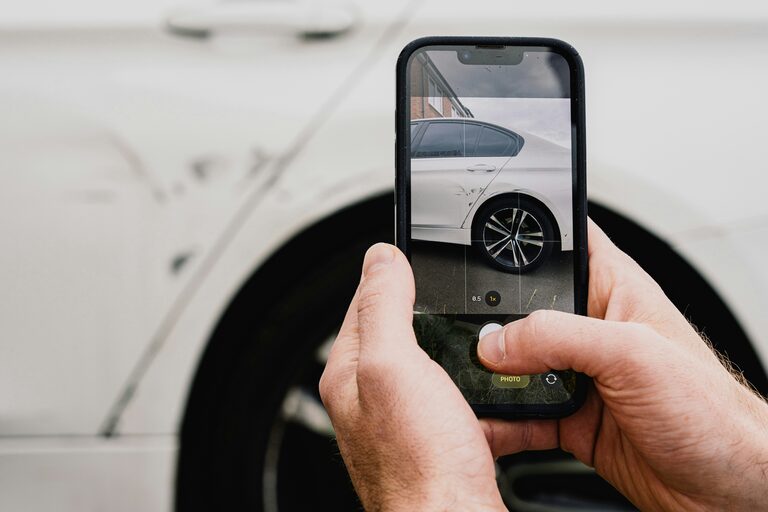 Autobesitzer fotografiert mit dem Smartphone einen Schaden an seinem Fahrzeug